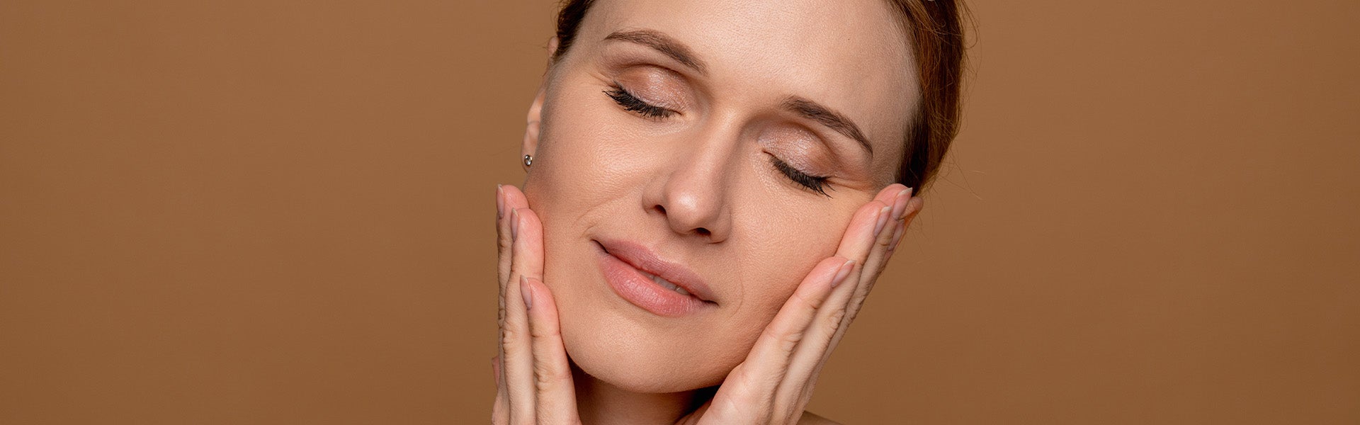 Close-up of a person gently touching their face, highlighting healthy skin and facial rejuvenation treatments.