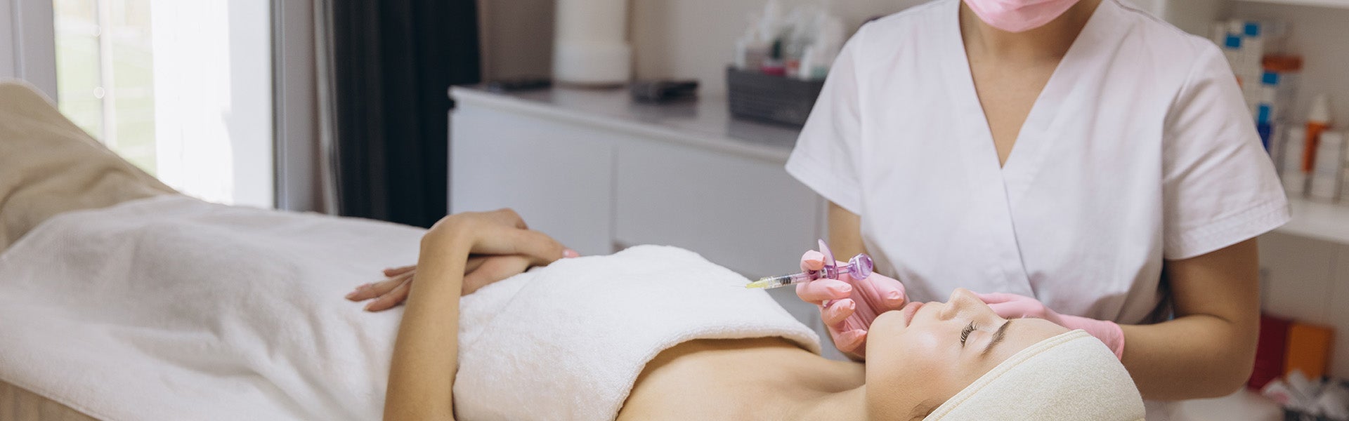 Client receiving a professional facial skincare treatment at a modern aesthetic clinic.