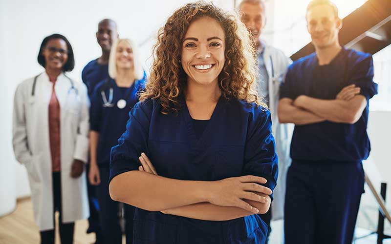 A diverse group of smiling healthcare professionals, including doctors and nurses, standing together.